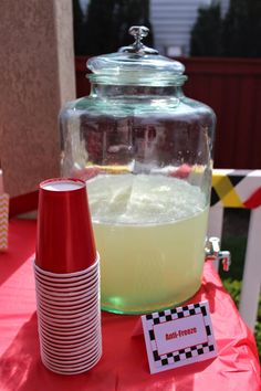 a table topped with a glass jar filled with liquid next to a red and white striped cup