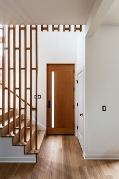 an empty hallway with wooden stairs and white walls