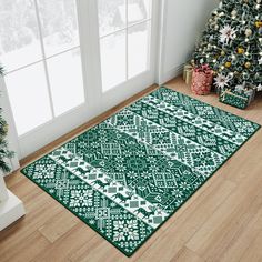 a green and white area rug in front of a christmas tree