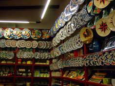 there are many plates on the shelves in this store, all different colors and designs