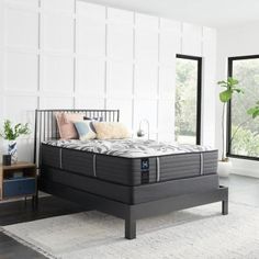 an image of a bedroom setting with mattresses and pillows on the bed frame in front of large windows