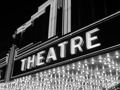 the theatre marquee lit up at night in black and white with lights all around it