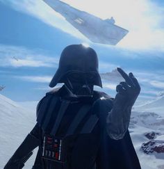 a man dressed as darth vader waves to the camera while standing on top of a snow covered mountain