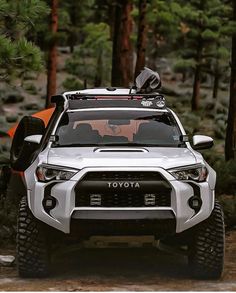 the front end of a white four - doored toyota truck parked on a forest trail