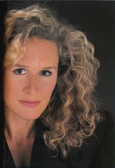 a woman with blonde hair and blue eyes looking at the camera while wearing a black shirt