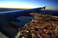 an airplane wing flying over a city at night