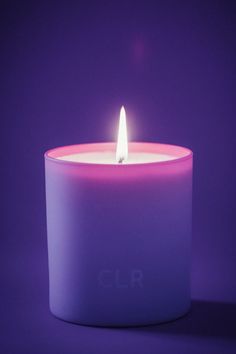 a lit candle with the word clr on it in front of a purple background