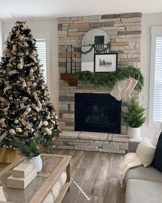 a living room decorated for christmas with a tree in the corner and stockings on the mantel