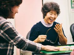 two women sitting at a table laughing and having fun with each other while holding their hands together