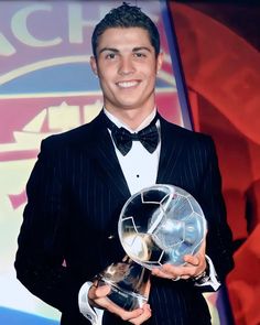 a man in a tuxedo holding an award for best young professional soccer player