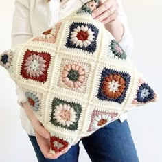 a woman is holding a crocheted pillow in her hands