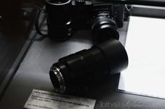 a black camera sitting on top of a table next to a white paper and pen