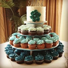 a three tiered cake with cupcakes on it