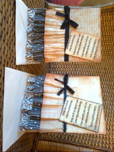 two folded greeting cards with black ribbon on them sitting on top of a wicker chair