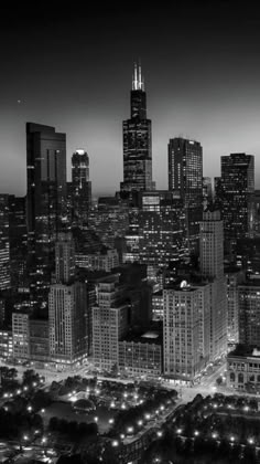 black and white photo of the chicago skyline at night with skyscrapers in the foreground