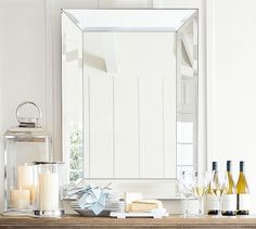 a table with candles and bottles on it next to a large mirror in the corner