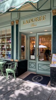 the outside of a store with tables and chairs on the sidewalk in front of it