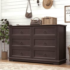 a brown dresser sitting on top of a wooden floor next to a potted plant