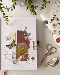 an open notebook with paper, scissors and other things on it next to some flowers