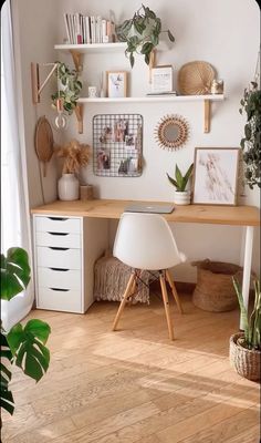 a white desk with some plants and pictures on the wall above it in a living room