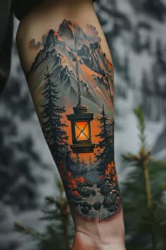 a person with a tattoo on their arm holding a lantern in front of mountains and trees