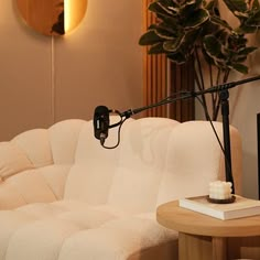 a white couch sitting next to a table with a lamp on it's side