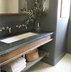 a bathroom sink sitting under a mirror next to a wooden shelf with towels on it