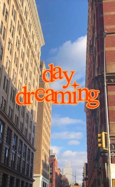 an orange sign that says day dreaming hanging from the side of a building on a city street