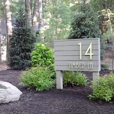 a sign that is in the middle of some bushes and trees with numbers on it