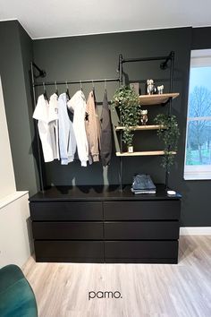 a black dresser with clothes hanging on it