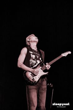 a man playing a guitar while standing on stage