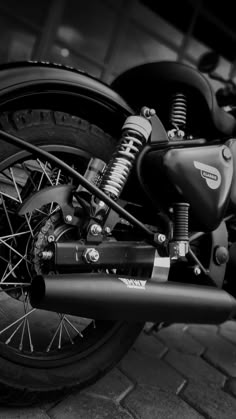 black and white photograph of a motorcycle parked in front of a building with brick floors