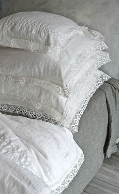 a pile of white pillows sitting on top of a bed