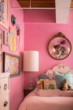 a bedroom with pink walls and pictures on the wall