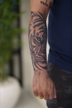 a man with a tiger tattoo on his arm pointing at the camera while he is holding something in his hand