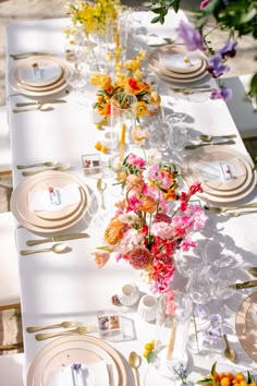 a long table with plates and flowers on it