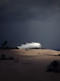 a building that is sitting in the middle of some sand with dark clouds above it