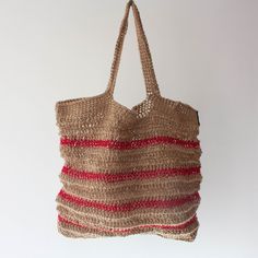 a straw bag hanging from a hook on a white wall with red and beige stripes