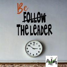 a clock sitting on top of a wall with the words be follow the leader above it