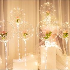 three clear balloons with roses in them on top of a table