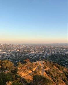 a view of the city from atop a hill with trees and hills in the foreground