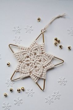 a crocheted star ornament with bells around it on a white surface