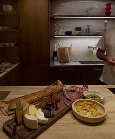 a man standing in front of a kitchen counter with food on the counter and wine bottles