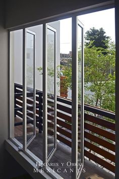 an open window on the side of a building with trees in the backround