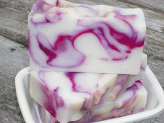 three soap bars stacked on top of each other in a white bowl with purple swirls