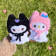 two crocheted hello kitty and penguin finger puppets are shown in front of some grass