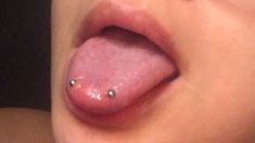 a close up of a person's tongue with piercings on it