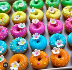 there are many colorful donuts in the box together and one is decorated with flowers