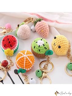 several crocheted fruit keychains are shown on a white surface with other items in the background