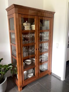 a wooden china cabinet with glass doors and shelves